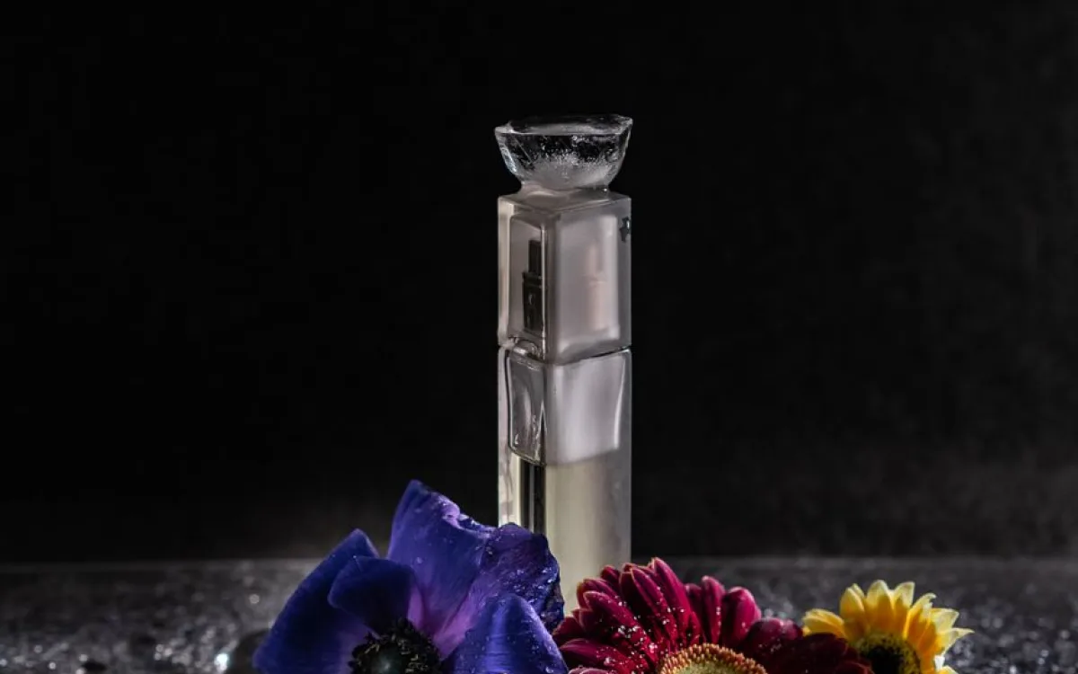 Flakon perfum na czarnym tle otoczony kolorowymi kwiatami