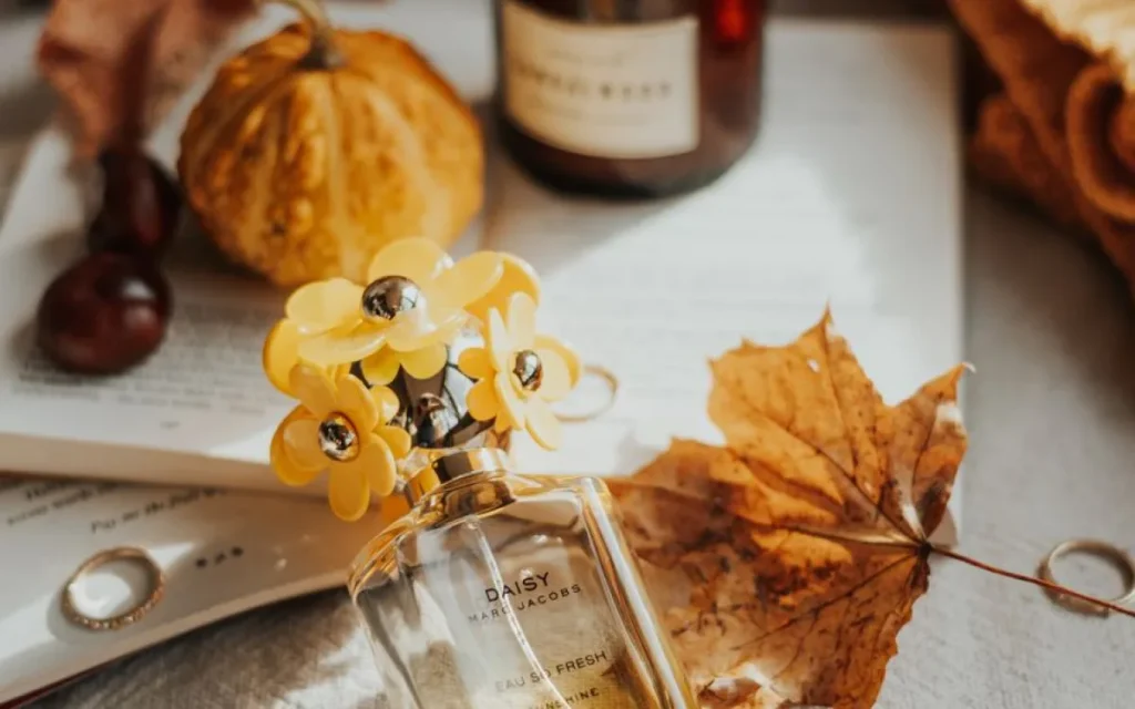 Flakon perfum Marc Jacobs Daisy wśród jesiennych liści i dyni
